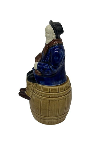 Rare stoneware musical liqueur bottle depicting a hurdy-gurdy player on a barrel, functional musical mechanism