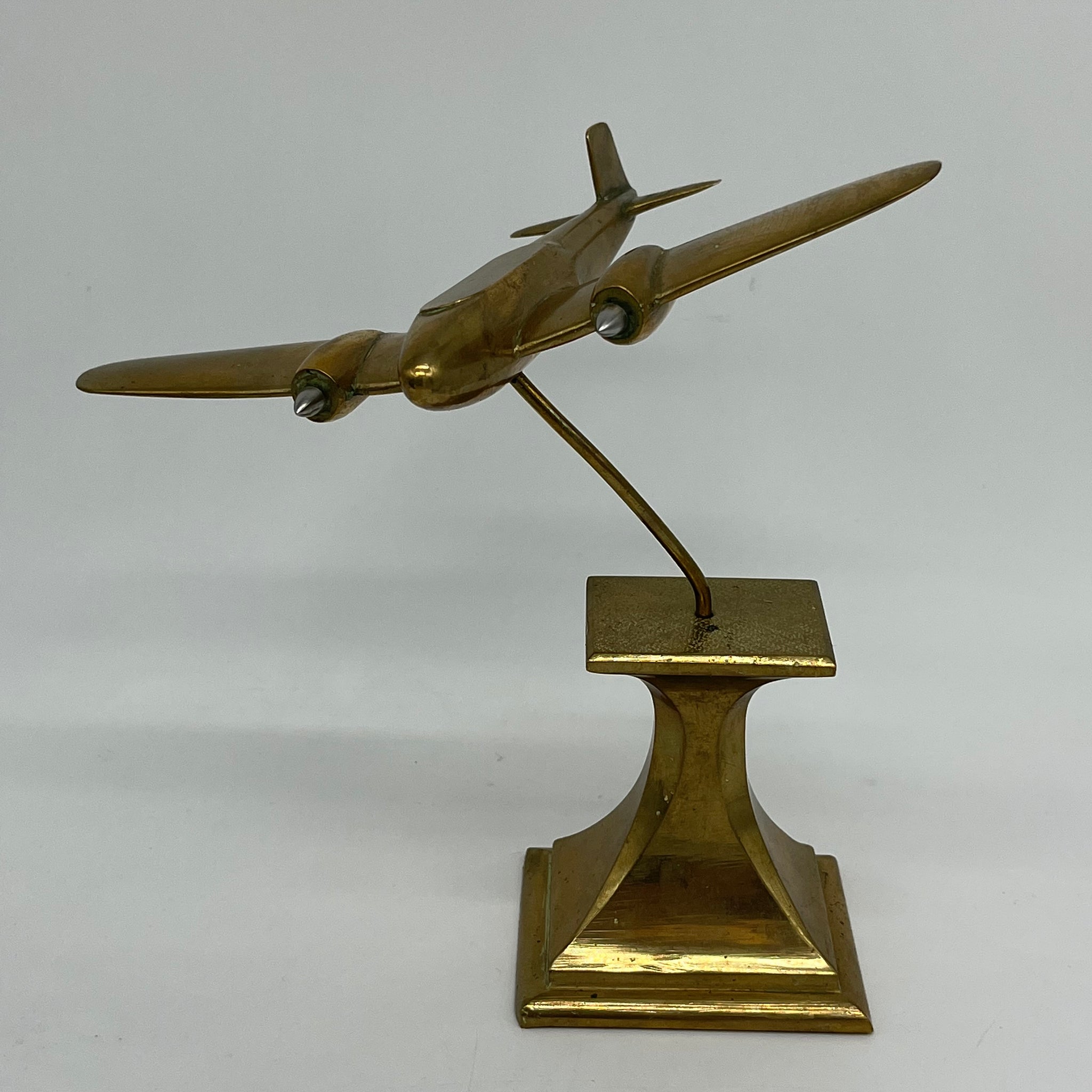 Sleek brass airplane model, on base